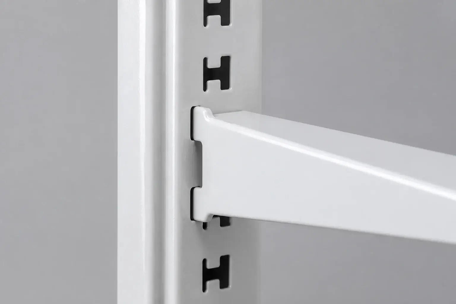 Close up of a gondola shelving upright showing H slot openings at fifty millimetre pitch with a shelf bracket hooked into position